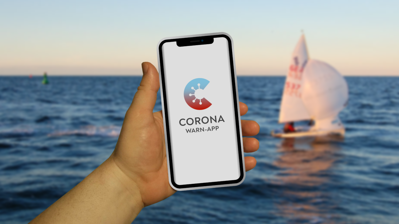 Gratis Download von iXimus.de: Bild der Corona-Warn-App mit Smartphone in Hand - Urlaub, See, Meer